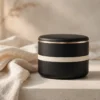 Boîtier élégant noir et doré sur un linge ivoire, ambiance premium et discrète