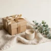 Coffret cadeau discret fermé avec ruban doré, bougie et eucalyptus — premier sextoy chez Hédonia